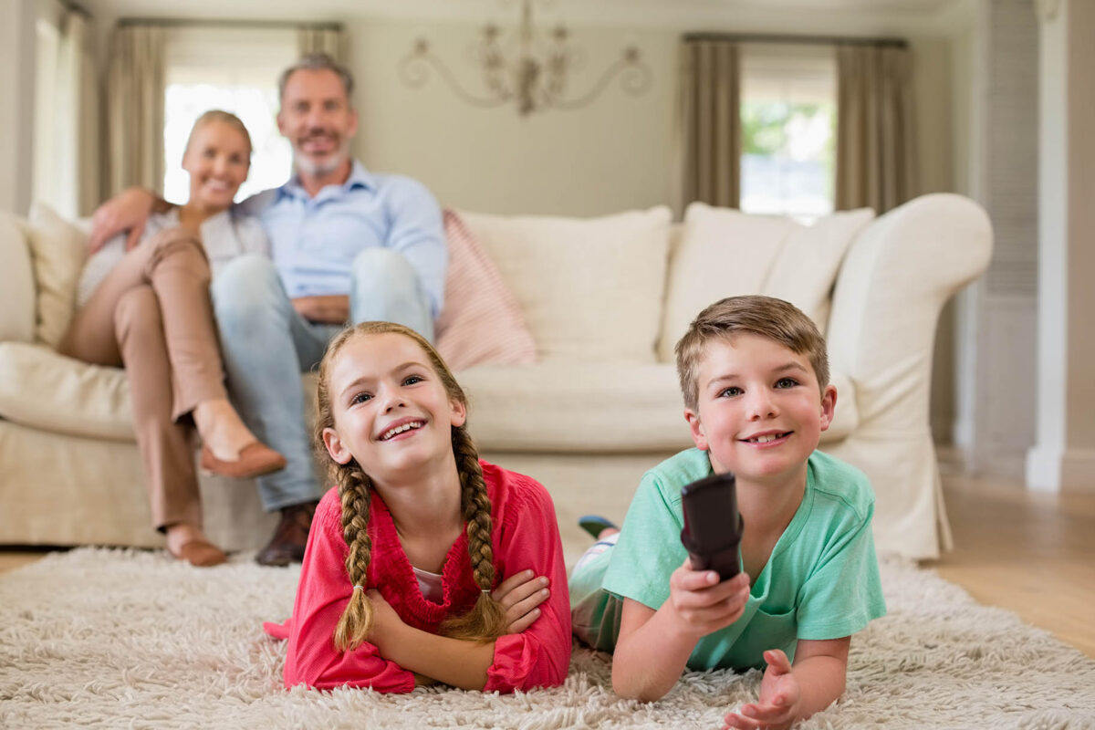 Parents and kids watching television in living room